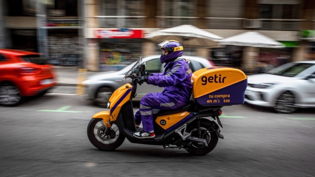 <p>A courier for the food delivery service Getir rides along a street in Barcelona, Spain.</p>