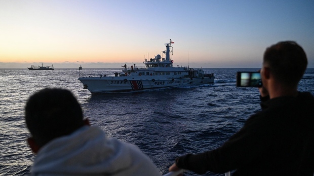 Philippine Coast Guard personnel film a China Coast Guard vessel during a supply mission in the disputed South China Sea on March 5. Photographer: Jam Sta Rosa/AFP/Getty Images