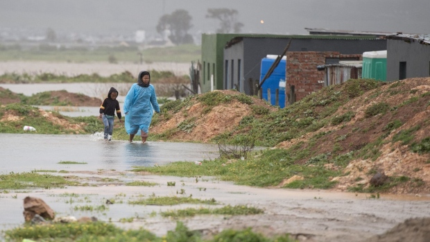People walk through water and mud during heavy flooding near Somerset West, South Africa, in September 2023. Photographer: Rodger Bosch/AFP/Getty Images