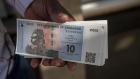 A customer displays a bundle of brand new ZiG banknotes after collecting them from a bank in Harare, Zimbabwe, on Tuesday, April 30, 2024. The southern African nation that’s had bouts of hyperinflation and triple-digit inflation introduced ZiG, short for Zimbabwe Gold on April 5. Photographer: Cynthia R Matonhodze/Bloomberg